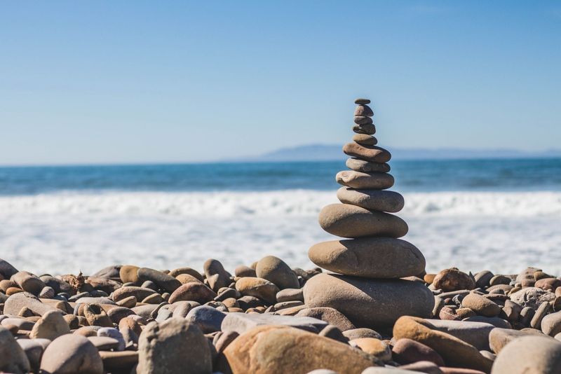 Aufgeschichteter Steinturm an einem Kieselstrand vor dem Meer