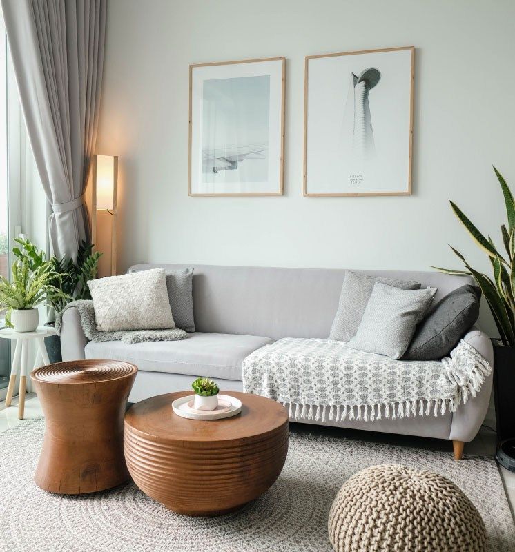 Wohnlicher Raum mit Sofa, Holztischchen, Pflanze und Bildern an der Wand